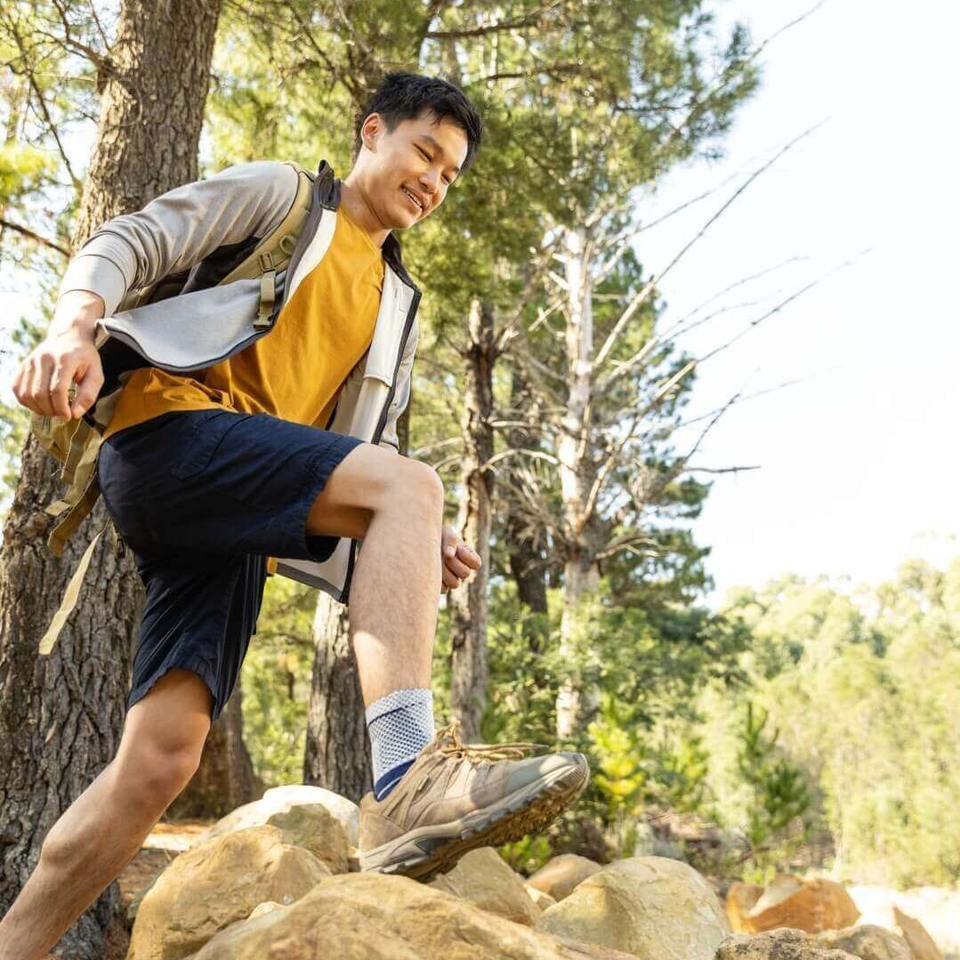 Das Bild zeigt einen Wanderer im Wald, der eine MalleoTrain Fußgelenkbandage trägt. 